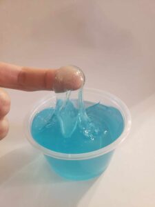 a finger dipped into clear blue slime